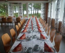 Langbord dekt til selskap ved Nesholmen med utsikt over vatnet